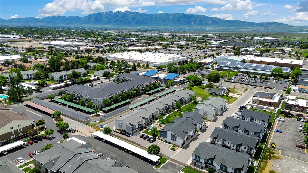 Expansive aerial view showcasing multiple residential buildings, covered parking structures, and a distant mountainous backdrop