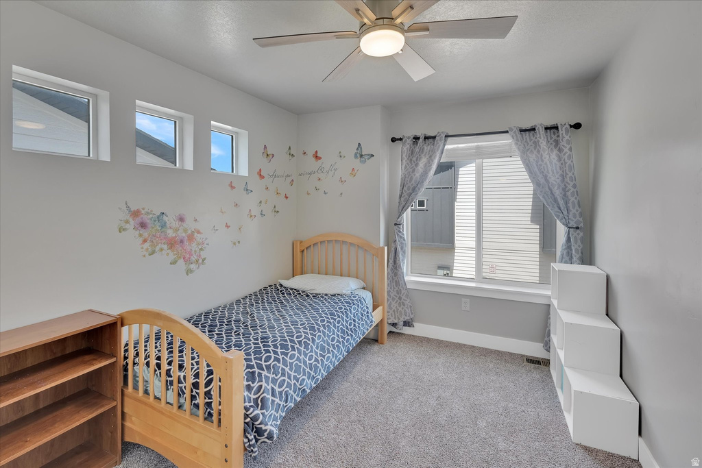 Carpeted room featuring a ceiling fan with integrated lighting, a large window, three transom windows, and light gray wall paint