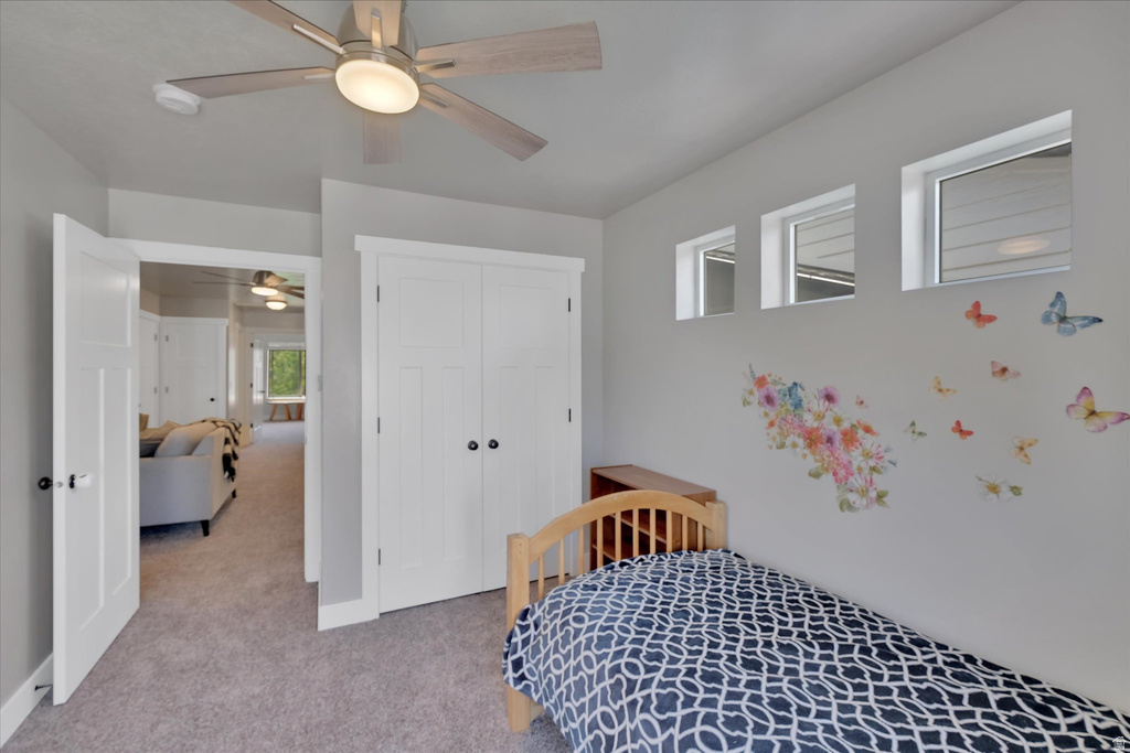 Carpeted room with a ceiling fan, three transom windows, and a double-door closet with black hardware