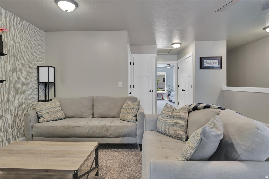 Carpeted living area featuring a geometric accent wall, flush-mount lighting, white trim, and doors with dark hardware