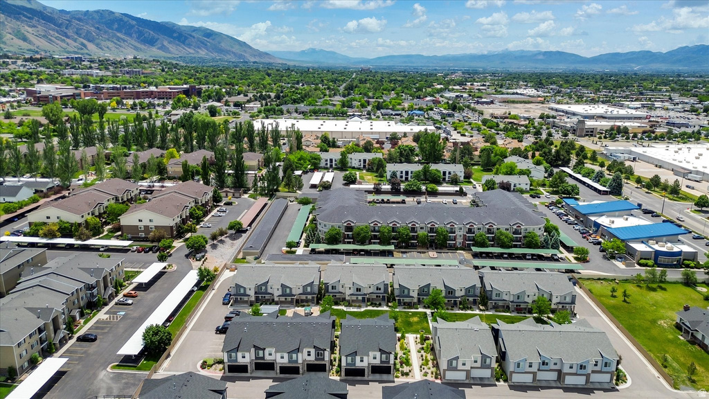 Expansive aerial panorama showcasing a residential community with multi-story buildings and townhomes, featuring multiple covered parking structures and surrounding green spaces