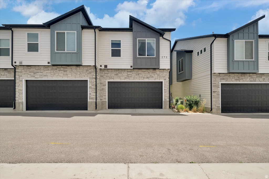 Modern townhome exterior featuring stone veneer and white horizontal siding
