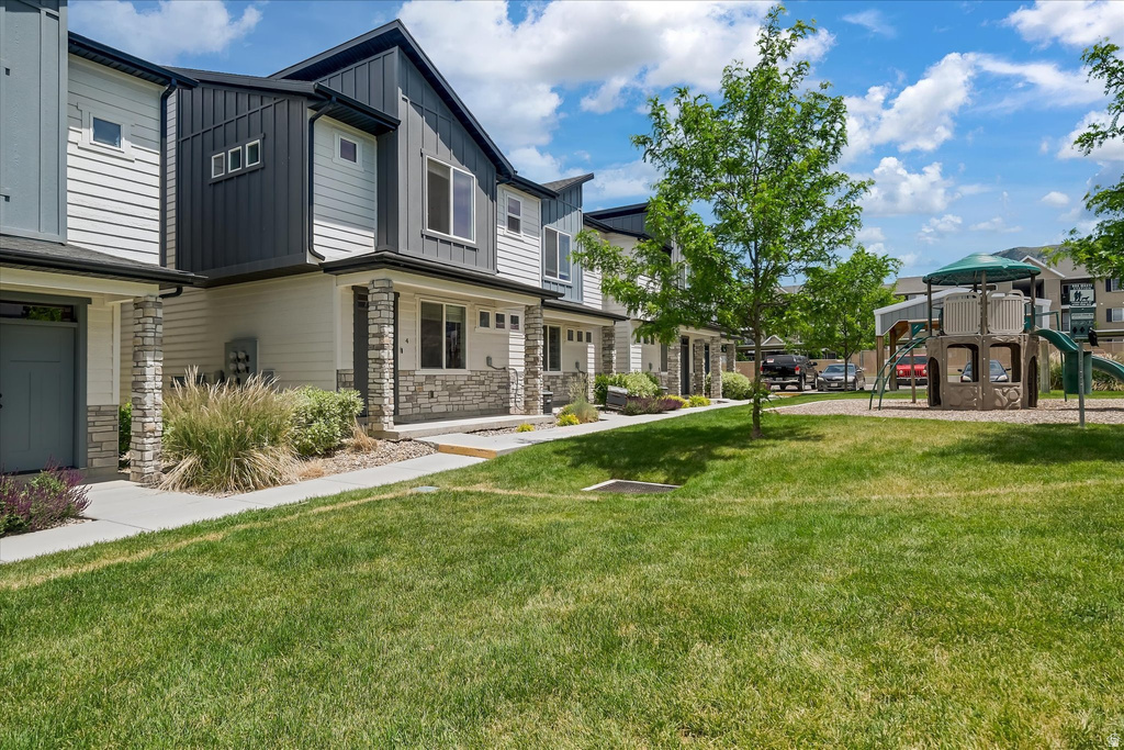 Manicured green space fronting contemporary townhomes with stone veneer and vertical siding accents