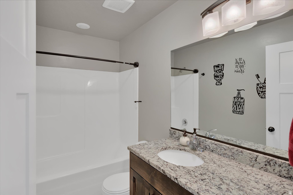 Bathroom featuring a white tub-shower combination, a vanity with a white oval sink, a light-toned speckled countertop, and a large mirror with integrated lighting