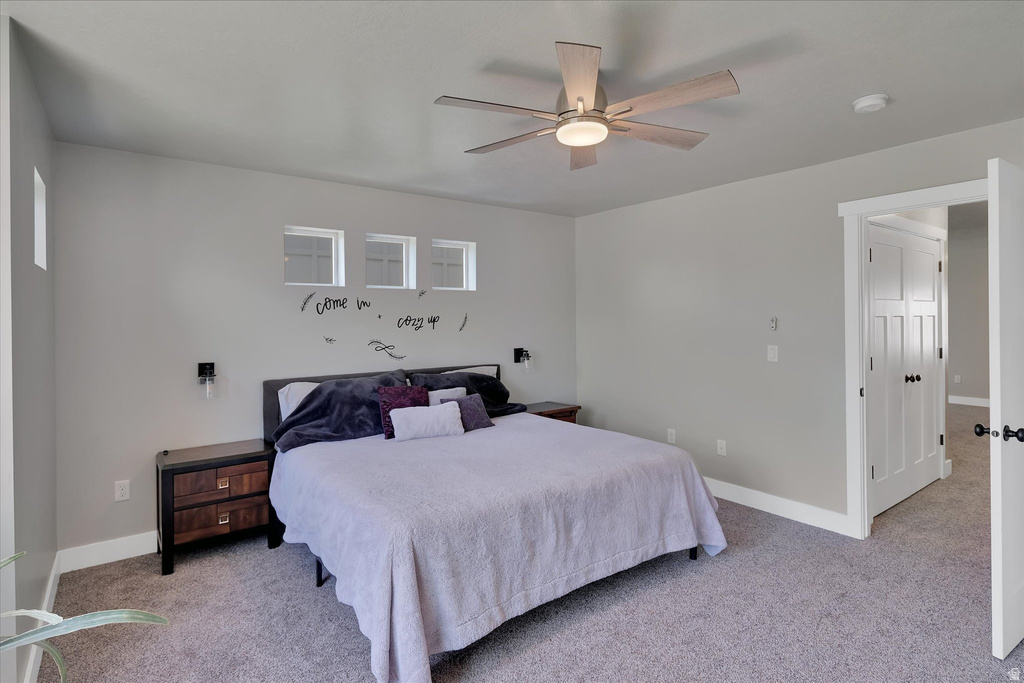 Carpeted bedroom with a ceiling fan light fixture