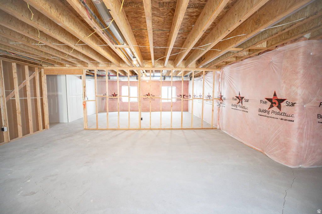 Unfinished basement featuring exposed joists, concrete flooring, framed wall partitions, and insulated exterior walls