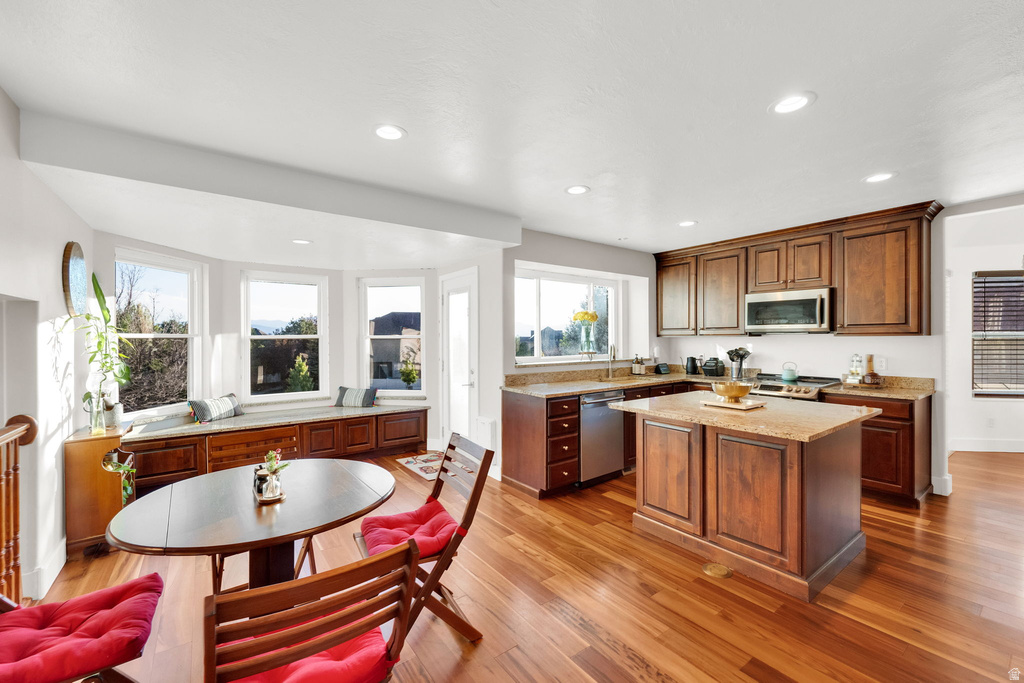 Open-concept kitchen and dining area featuring wood-finish flooring, recessed lighting, and a bay window with built-in storage