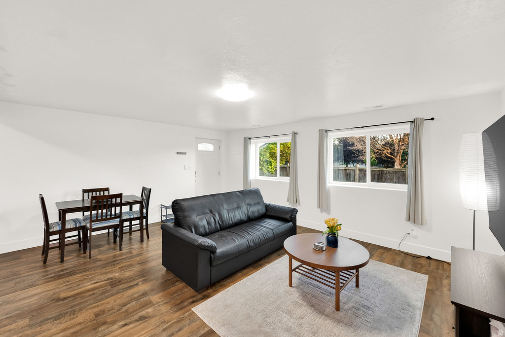 Open-concept living space featuring wood-finish flooring throughout, a white ceiling, recessed lighting, and a white entry door with an arched glass insert