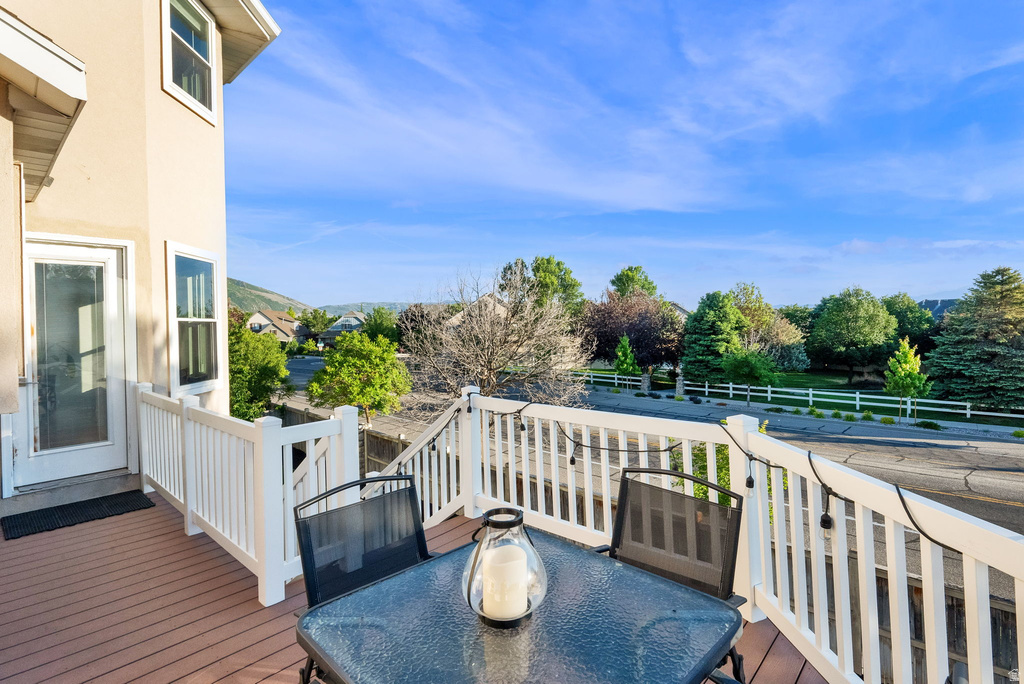 Spacious deck featuring composite wood-finish decking, white railings, and a transparent glass door