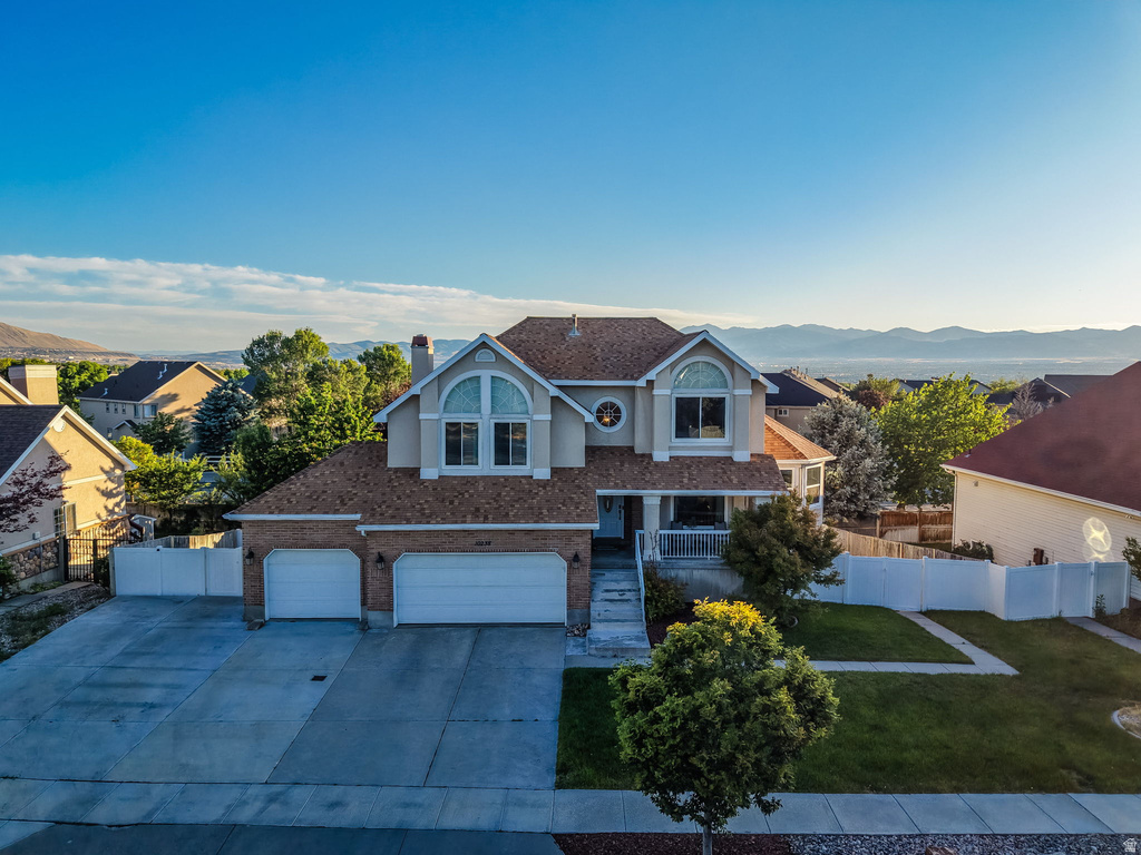 Two-story residence featuring a two-car garage, brick and stucco exterior, arched windows, and a covered porch