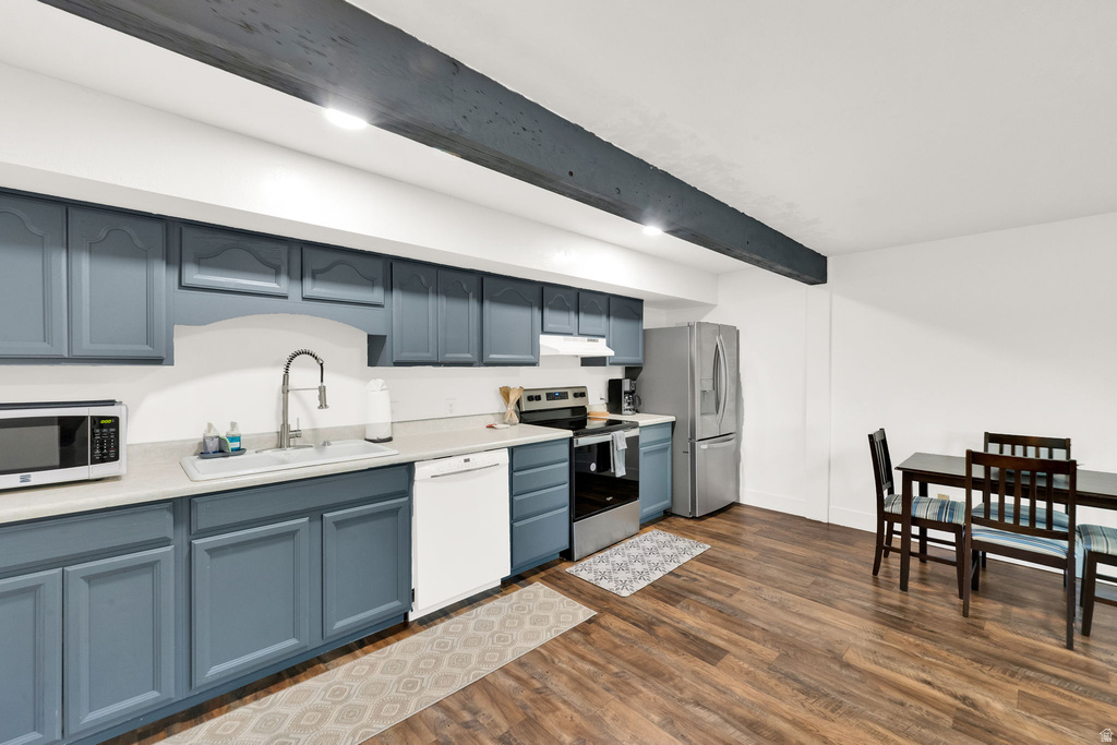 Kitchen featuring blue painted cabinetry with decorative molding, white countertops, wood-finish flooring, and a stainless steel refrigerator