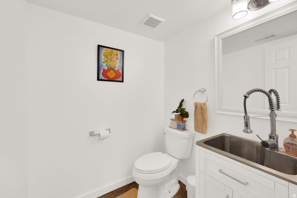 White vanity with stainless steel sink, pull-down faucet, and wall-mounted mirror