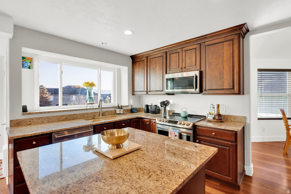 Kitchen featuring granite countertops, wood cabinetry, stainless steel appliances, a large window, and recessed lighting