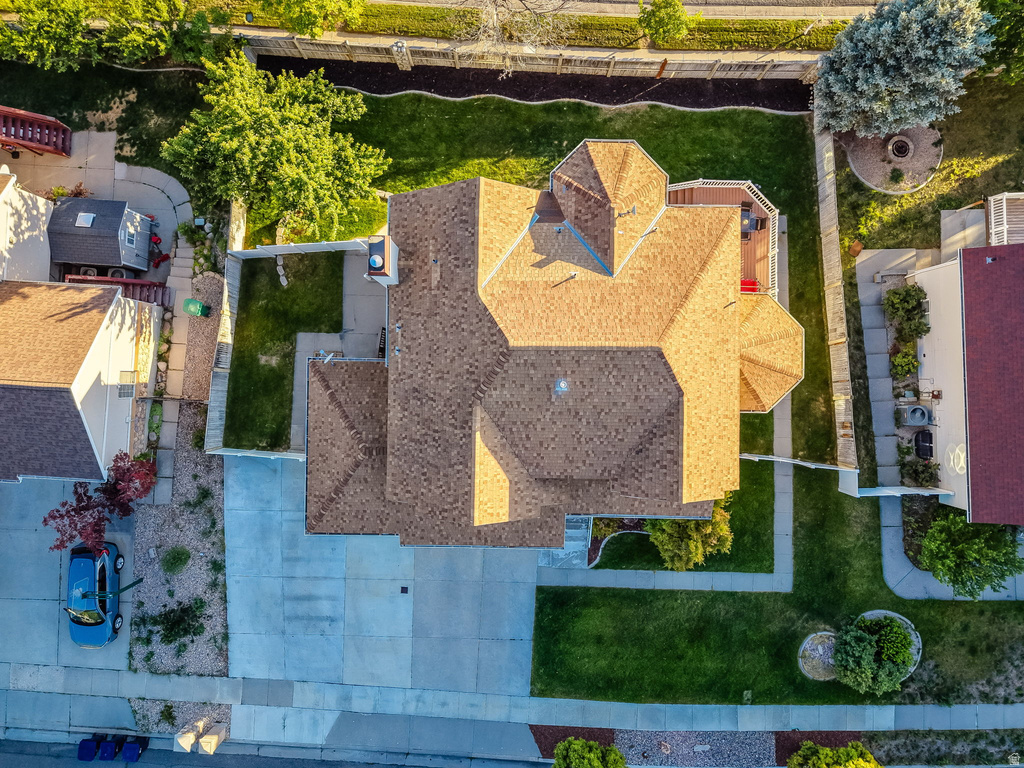 Aerial view featuring a multi-gabled roofline, concrete driveway, and expansive rear lawn