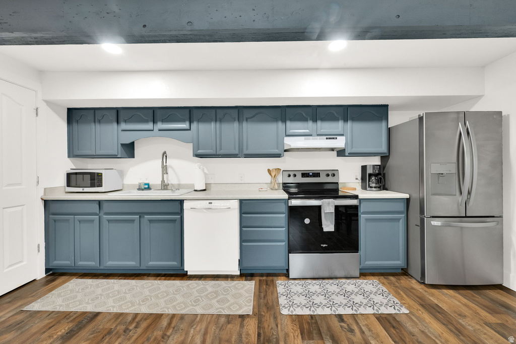 Kitchen featuring blue cabinetry with white countertops, stainless steel appliances, and wood-finish flooring