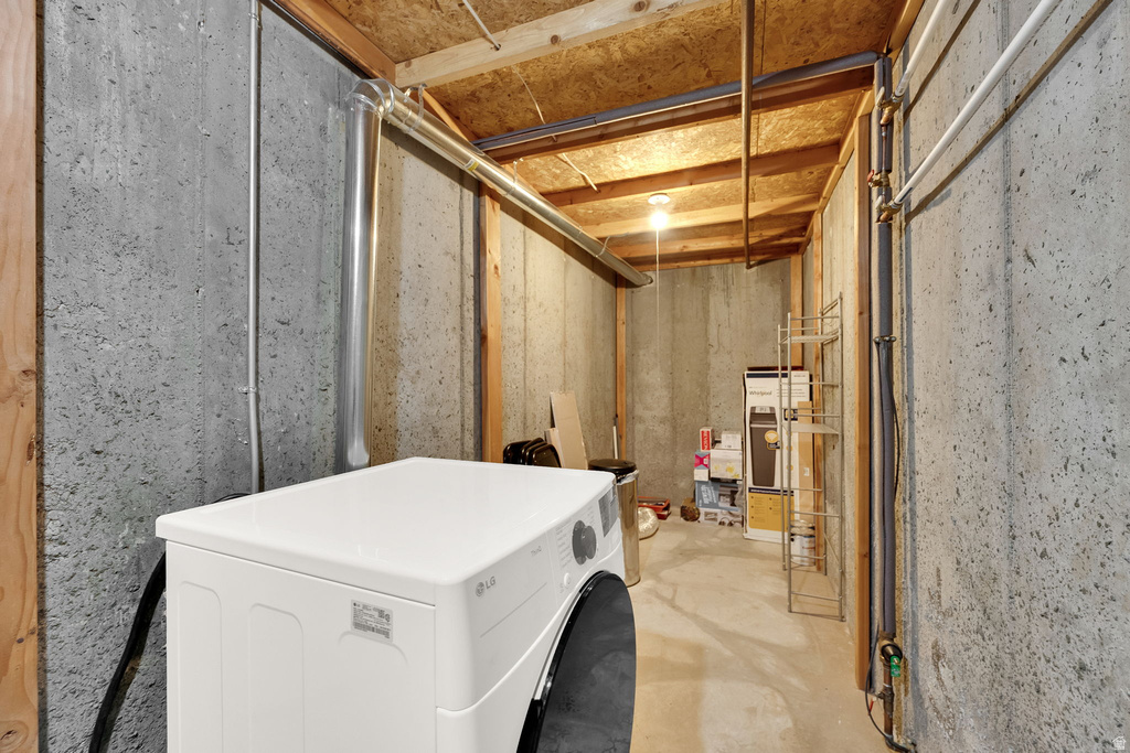 Utility area with concrete walls, exposed wood ceiling joists, and a concrete floor