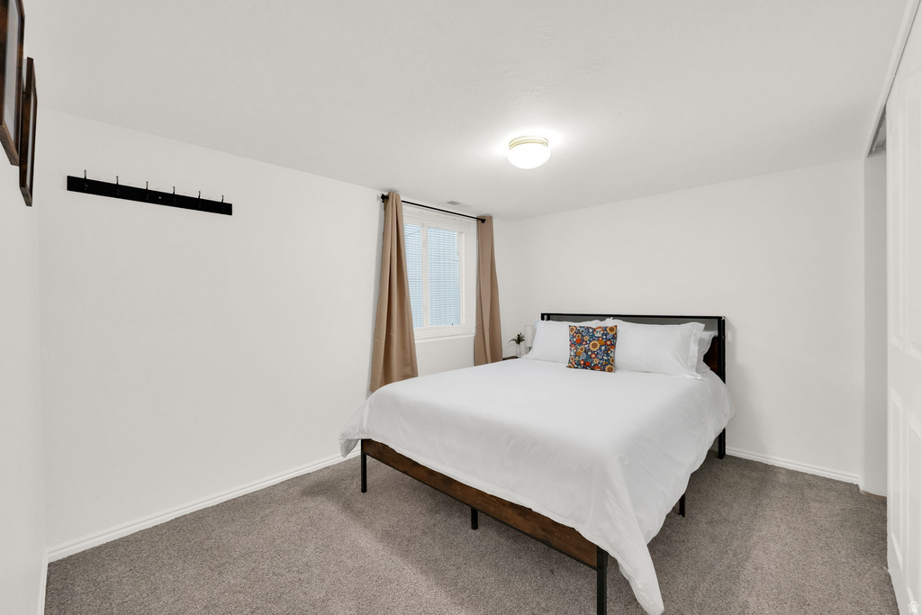 Carpeted room with a ceiling-mounted light fixture, white walls, and a window with drapes