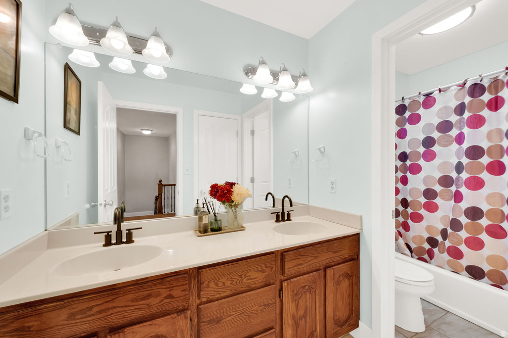 Dual vanity with wood-finish cabinetry, light-toned countertop, and dual bronze-finish gooseneck faucets