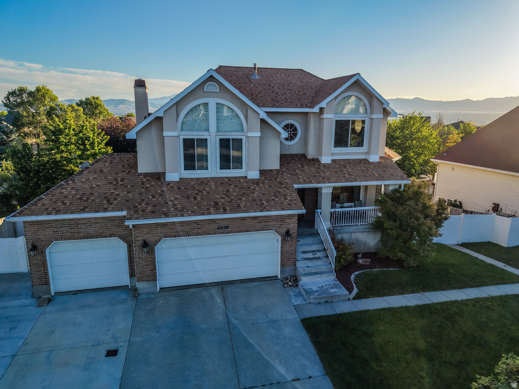Two-story residence featuring a brick and stucco facade, a two-car garage, and a covered front porch