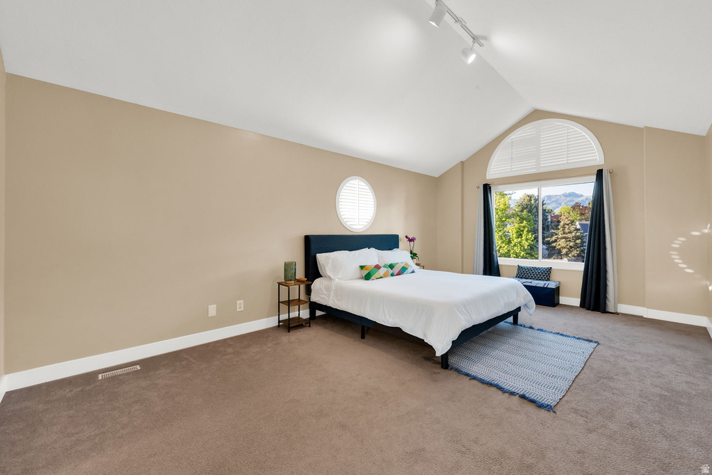 Spacious room featuring vaulted ceilings, a large arched window with white louvered shutters, and an additional oval window