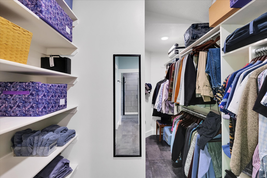 Walk-in closet featuring white built-in shelving, multiple hanging rods, recessed lighting, and dark wood-finish flooring