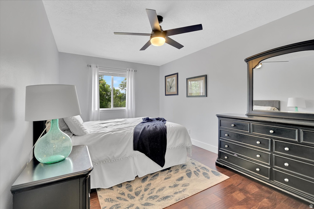 Bright interior space featuring a window with exterior scenery, dark wood-finish flooring, a ceiling fan with integrated lighting, and light-colored walls with white trim
