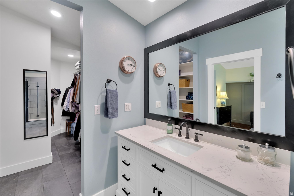 Bathroom vanity featuring a rectangular undermount sink, a light-toned countertop, and white cabinetry with dark hardware