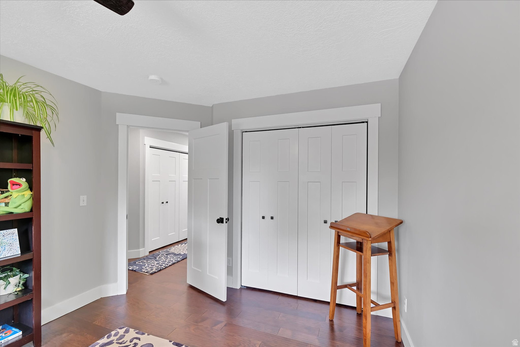 Room featuring wood-finish flooring, light gray walls, white trim, and white bi-fold closet doors with black hardware