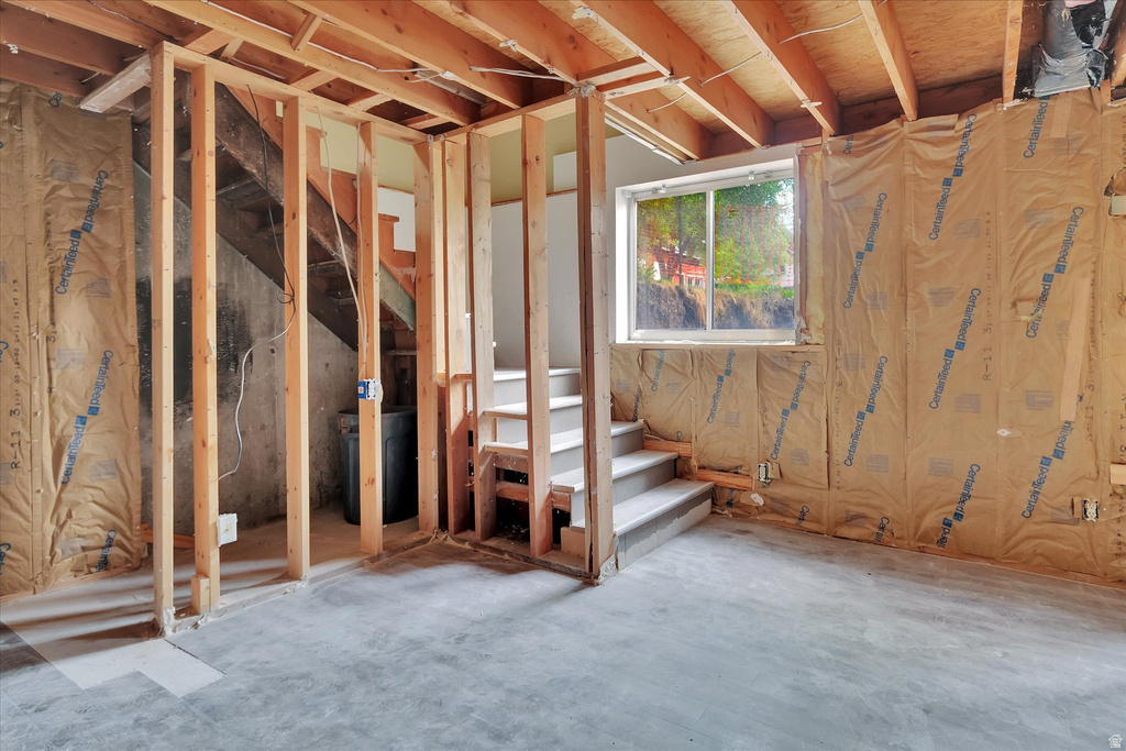 Unfinished lower level with exposed wood framing, concrete flooring, and a single-pane window