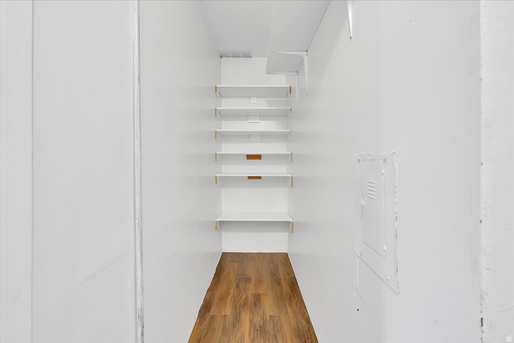 Recessed shelving unit with multiple white shelves, wood-finish flooring, and white painted walls