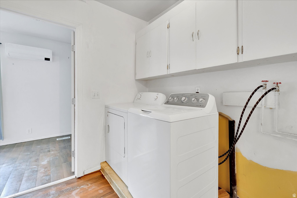 Dedicated laundry area featuring upper cabinetry, a utility sink base, and wood-finish flooring