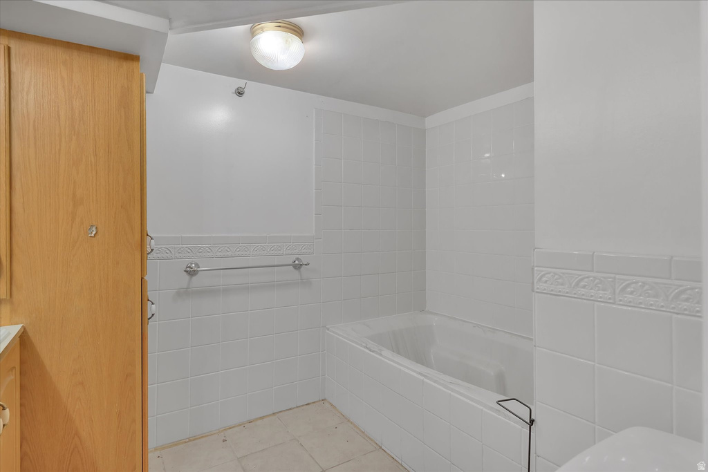 Soaking tub with white ceramic tile surround and decorative accent tile