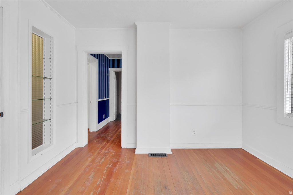 Hardwood flooring, white painted walls with wainscoting, and a built-in display cabinet with glass shelving