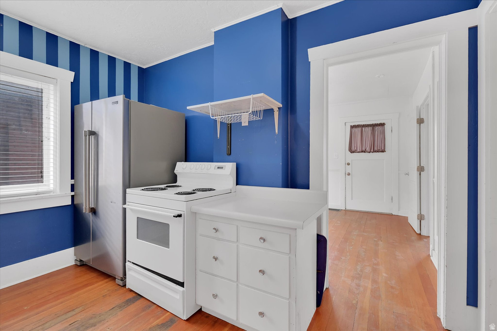Kitchen area featuring a stainless steel refrigerator, white electric range, and a white mobile island with storage