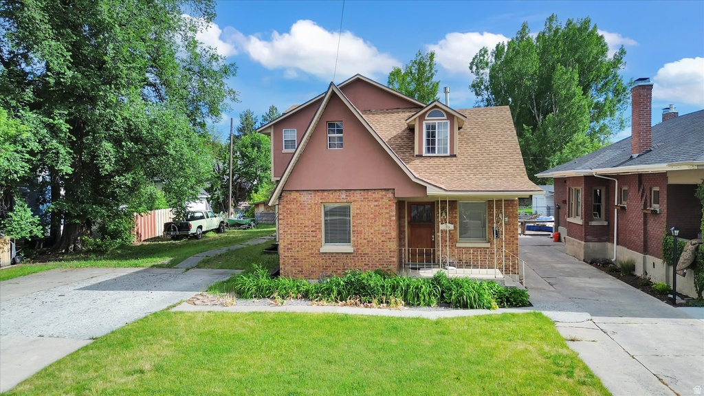 Brick facade residence featuring a front dormer, pitched shingle roof, and a covered entry porch