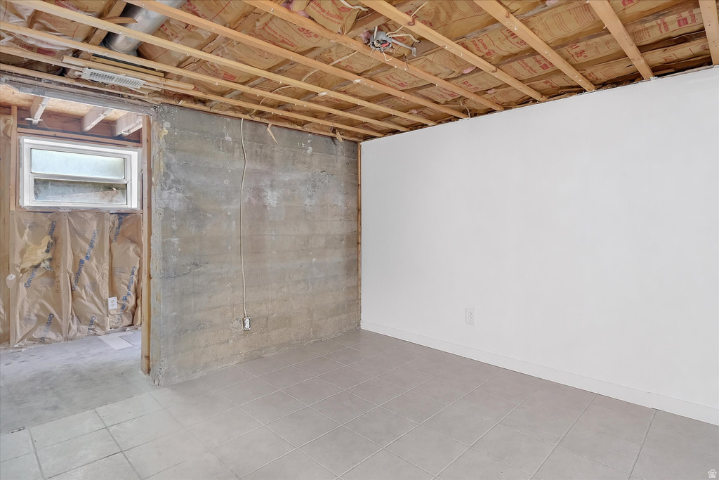 Lower level room featuring light gray tile flooring and a freshly painted white wall