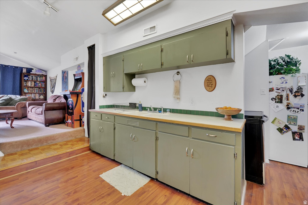 Kitchen area featuring light green cabinetry, a white countertop, and a green tile backsplash