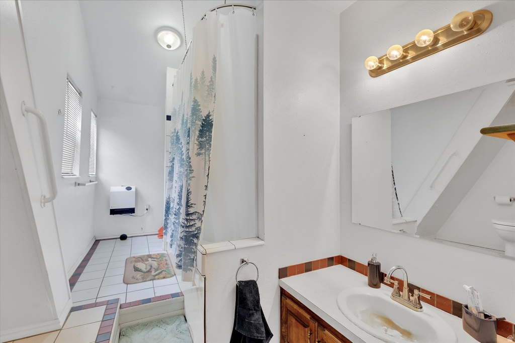Bathroom featuring a vanity with a white countertop and wood-finish cabinetry, a framed mirror, and a brass-toned four-bulb light fixture