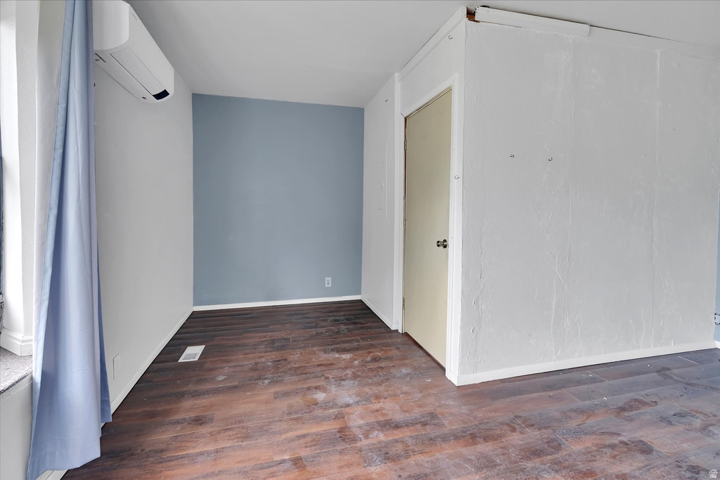 Room featuring wood-finish flooring, a light blue accent wall, and a split-system air conditioning unit
