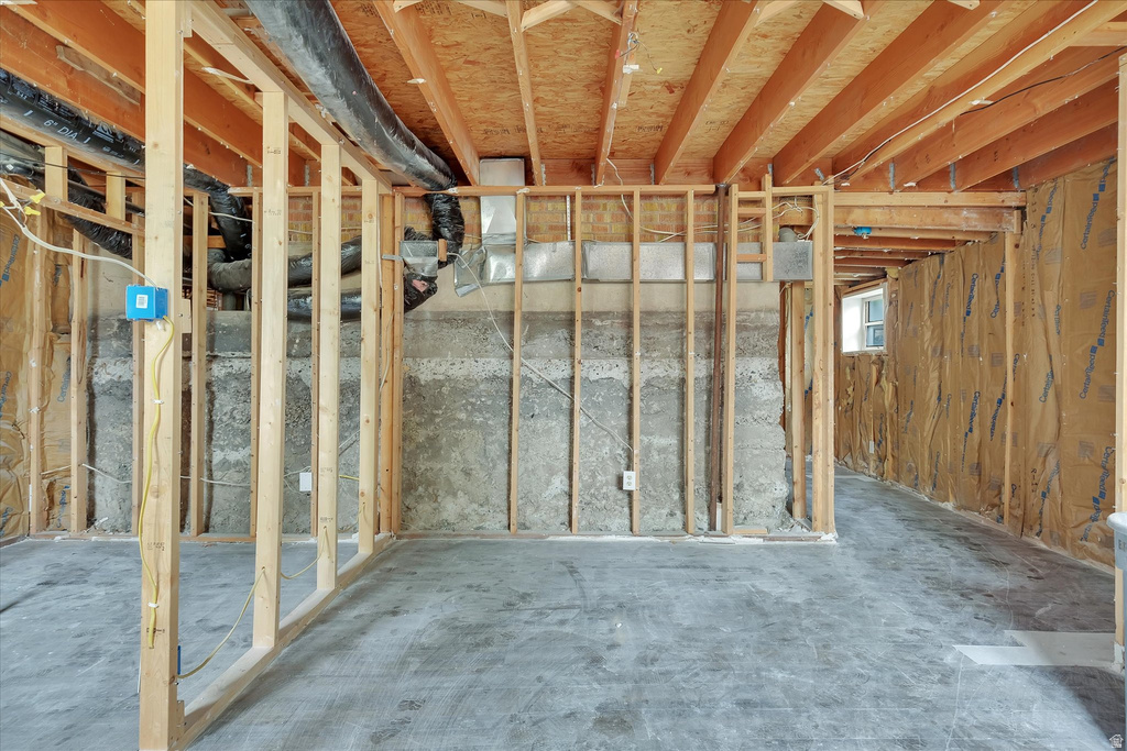 Unfinished basement space featuring exposed wood framing, concrete foundation walls, and concrete flooring