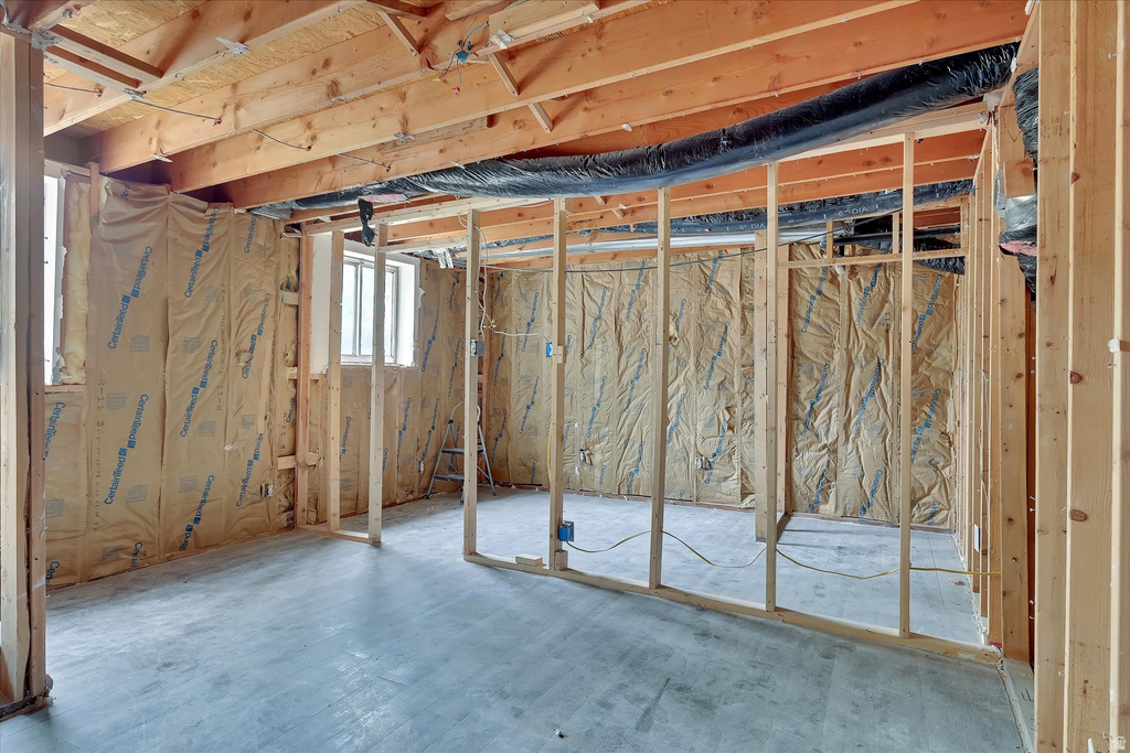 Unfinished lower level featuring exposed wood framing, concrete flooring, and insulated exterior walls