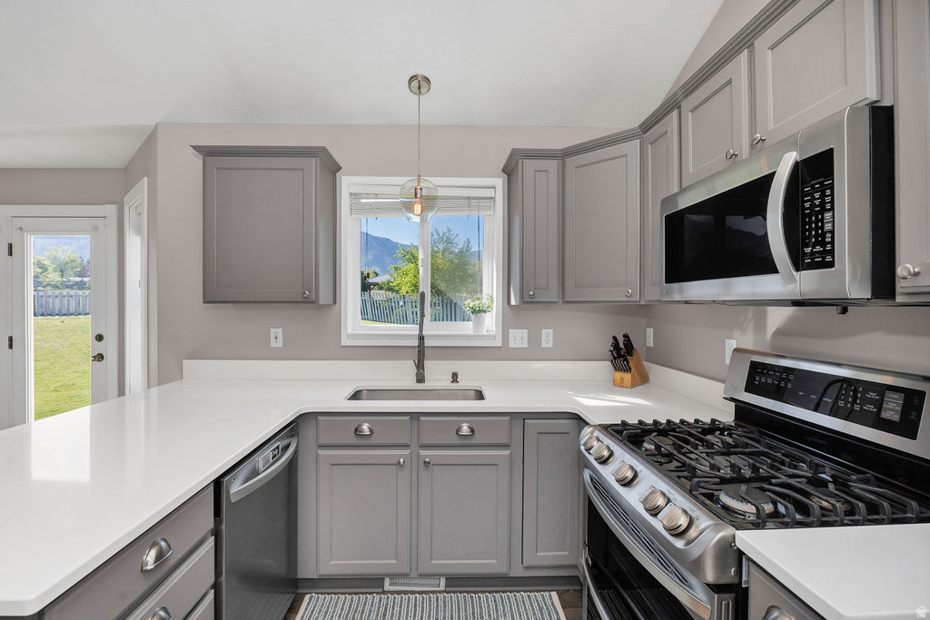 Kitchen featuring gray shaker cabinetry, white countertops, stainless steel appliances, and a window above the sink