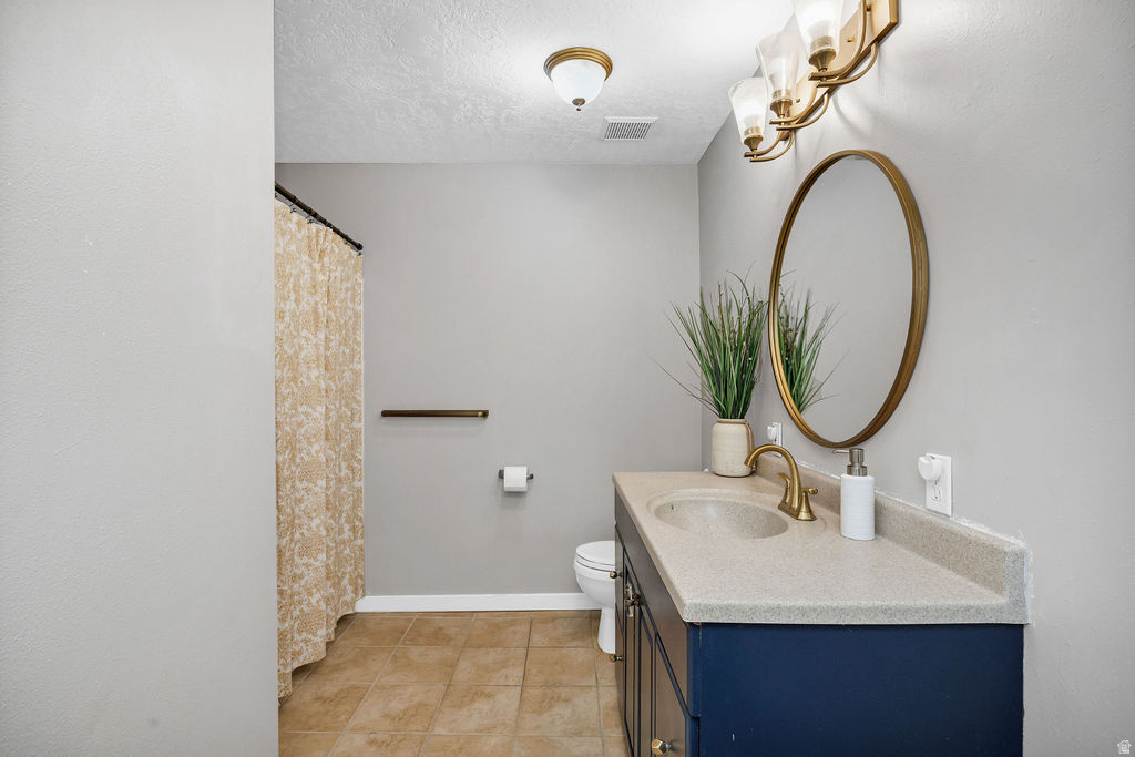 Bathroom featuring a vanity with a solid surface countertop, an undermount sink, a gold-toned faucet, and a round gold-framed mirror