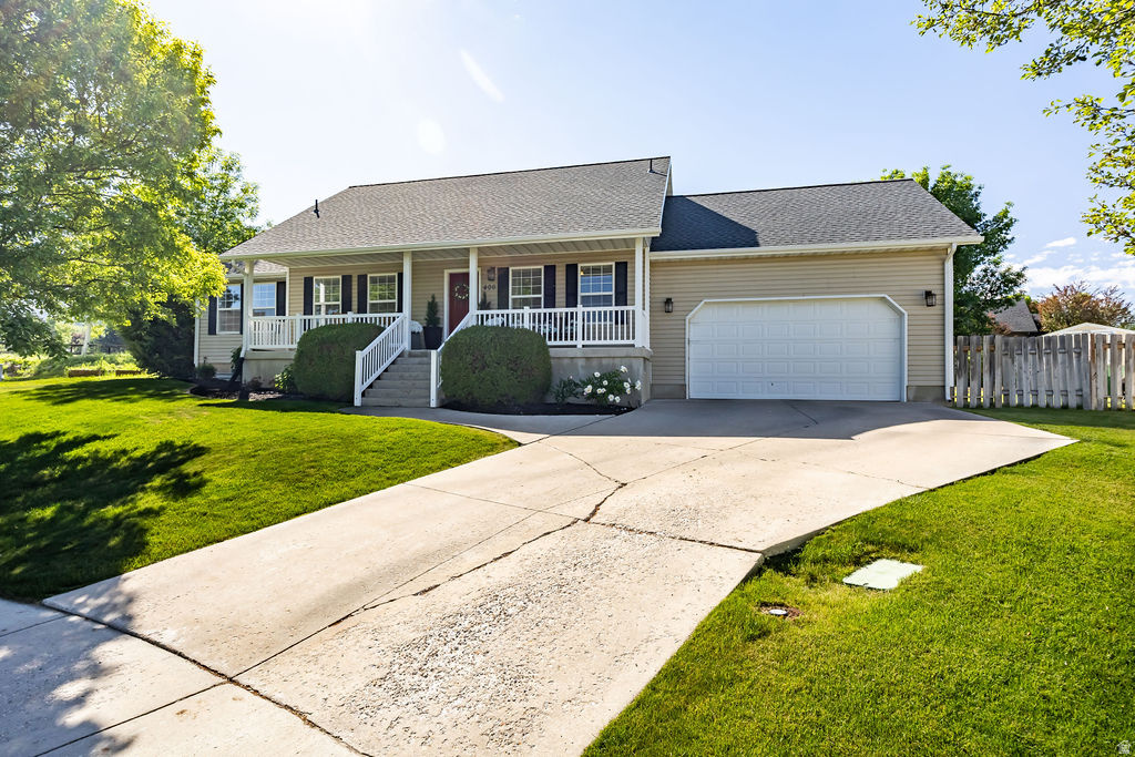 Traditional-style residence featuring a covered front porch with white railings, a two-car garage, and a concrete driveway
