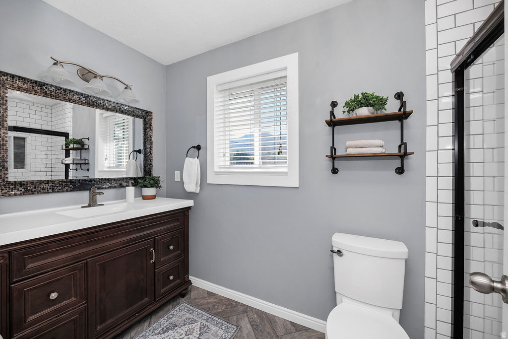 Bathroom featuring a dark wood vanity with a white countertop, mosaic-framed mirror, and wood-finish flooring