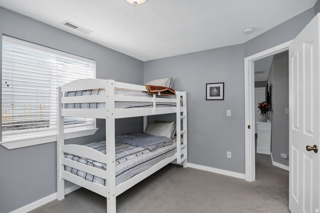 Light gray walls complement the neutral carpeting in this room, featuring a window with white blinds and white trim