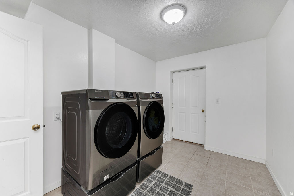 Dedicated laundry space featuring neutral tile flooring, white walls, and a flush-mount ceiling light fixture