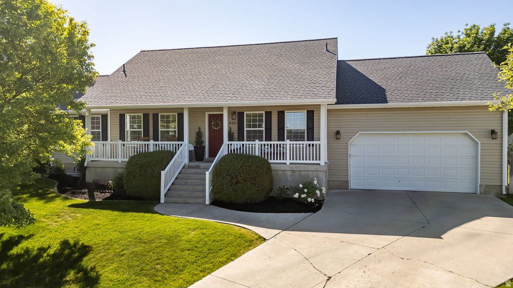 Ranch-style residence featuring a covered front porch with white railing, beige siding, a two-car garage, and a concrete driveway