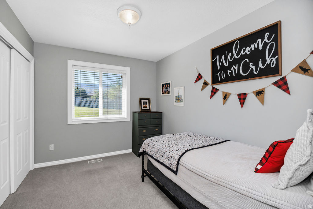 Bright room featuring a window with horizontal blinds, light gray walls, and matching gray carpeting