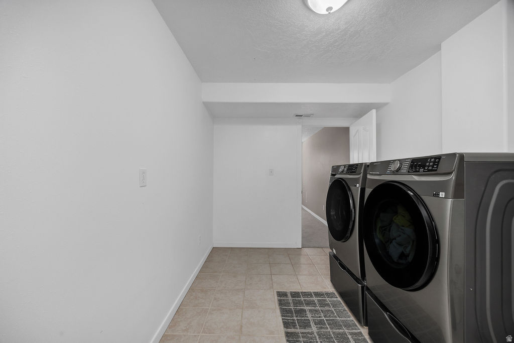 Dedicated laundry area featuring ceramic tile flooring, neutral wall tones, and a flush-mount ceiling light fixture